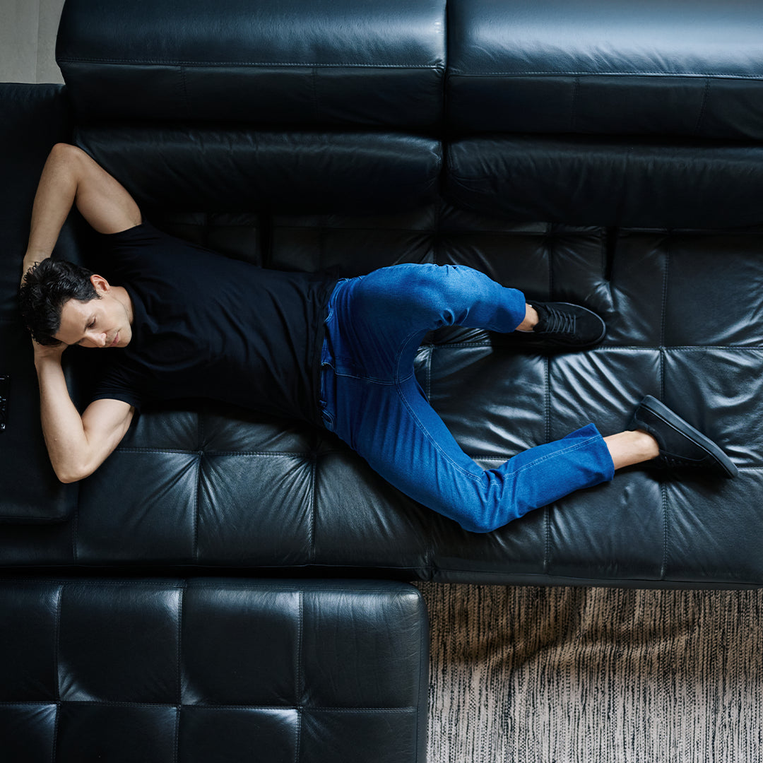 Homem deitado no sofá vestindo a Calça Jeans Comfort azul